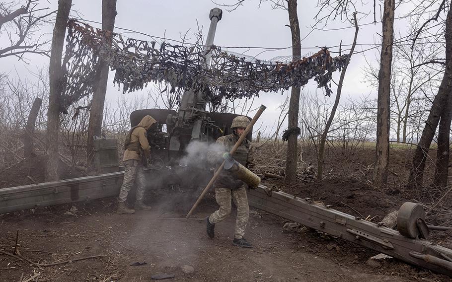 A Ukrainian soldier carries away an artillery shell casing after firing at Russian positions. 