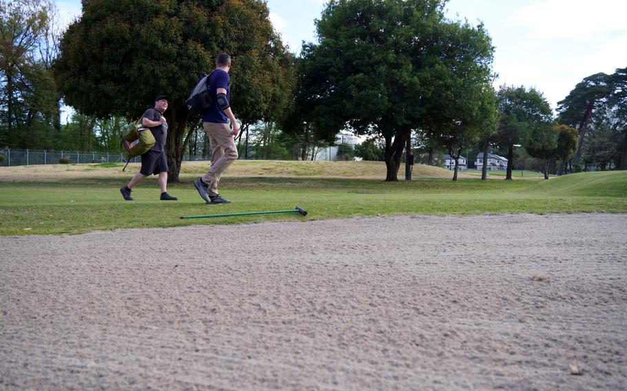 Air Force Senior Master Sgt. Joshua DeMotts, left, and Maj. Marshall Gries chat during a round of disc golf on the Par 3 course at Yokota Air Base, Japan, April 6, 2023.