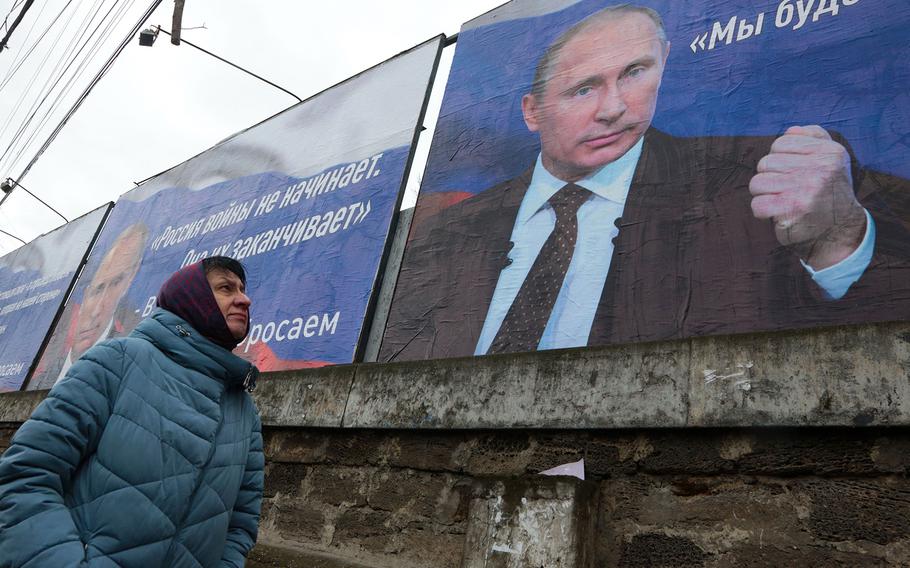 A woman walks past huge placards bearing images of Russian President Vladimir Putin and war slogans in the city of Simferopol, Crimea, on March 4, 2022. 