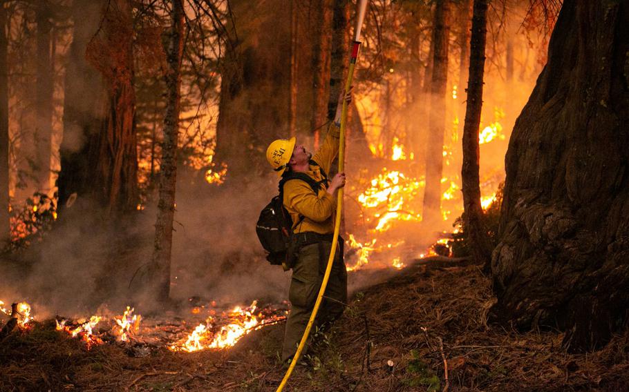 A firefighter works a control burn to head off a spot fire that started on a ridge behind a business on Hwy. 50 on Saturday, Aug. 28, 2021, in Strawberry, Calif. Firefighters continue to tackle the Caldor fire as it creeps closer to South Lake Tahoe.