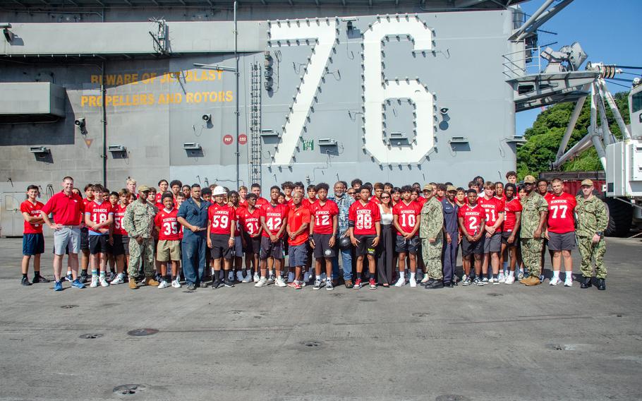 Members of the Nile C. Kinnick High School football team pose with family members aboard the aircraft carrier USS Ronald Reagan at Yokosuka Naval Base, Japan, Tuesday, Sept. 12, 2023.