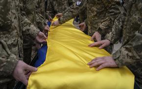 Ukrainian servicemen fold the national flag over the coffin of their comrade Andrii Neshodovskiy during the funeral ceremony in Kyiv, Ukraine, Saturday, March 25, 2023. (AP Photo/Evgeniy Maloletka)