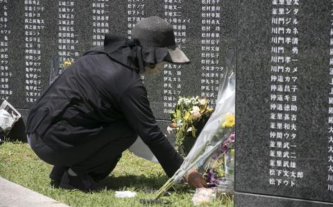 A visitor leaves an offering in front of the Cornerstone of Peace monument at Okinawa Peace Memorial Park during the annual Irei no Hi ceremony on June 23, 2022. 