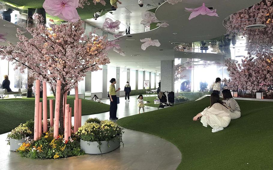 An indoor scene shows green carpet and pink-blossomed trees.
