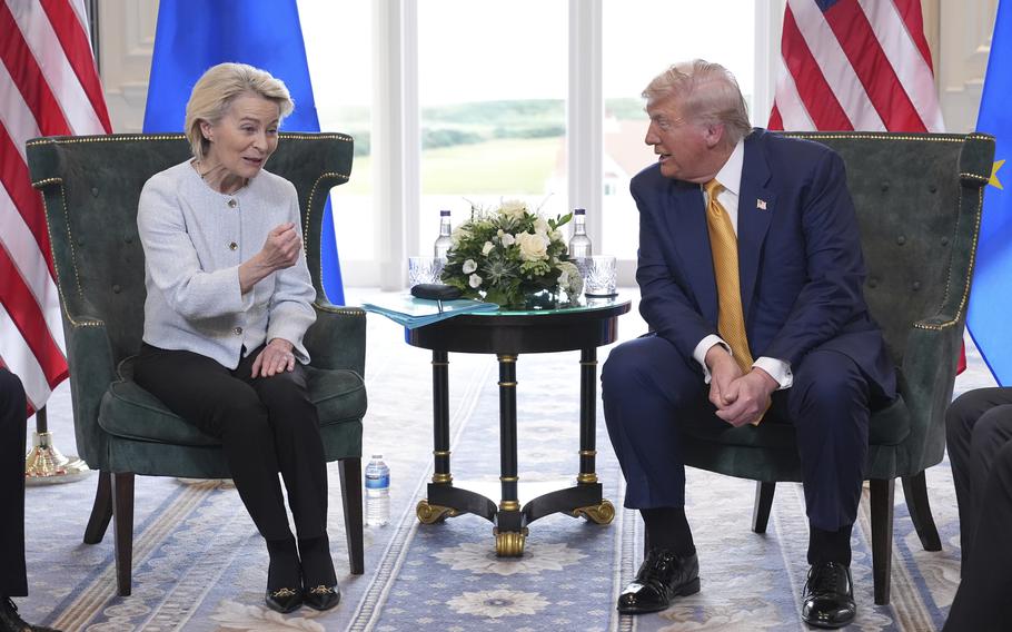 Von der Leyen makes a gesture with her right hand and Trump listens.