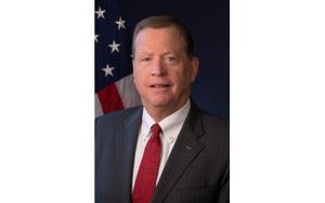 A vertical portrait of a man in a suit and tie.