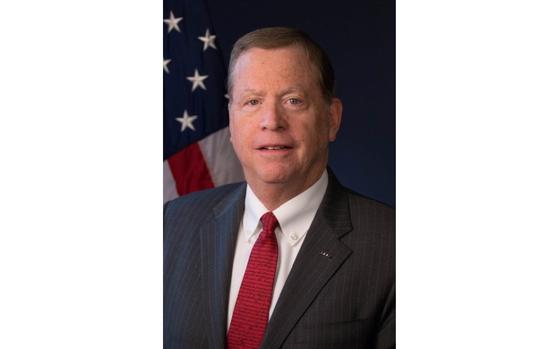 A vertical portrait of a man in a suit and tie.