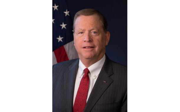 A vertical portrait of a man in a suit and tie.