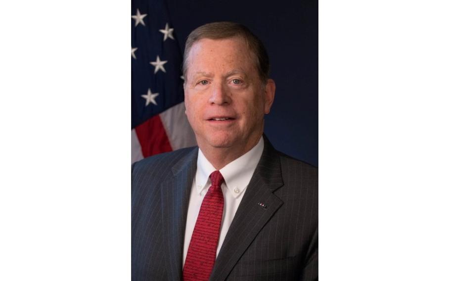 A vertical portrait of a man in a suit and tie.