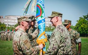 Air Force Gen. Dagvin Anderson, left, receives the flag from Navy Adm. Christopher Grady, vice chairman of the Joint Chiefs of Staff, during the U.S. Africa Command change of command ceremony in Stuttgart, Germany, on Aug. 15, 2025. The outgoing commander, Marine Gen. Michael Langley, can be seen at right.