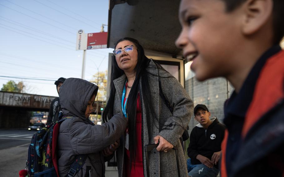 Mandi Buada Rivera waits to ride a bus with her children Jahir Emanuel Buada, 9, left, and Javier Andres Buada, 7, during their morning commute to school in D.C. on April 11. Rivera and her family are staying at a D.C. hotel along with hundreds of migrant families.