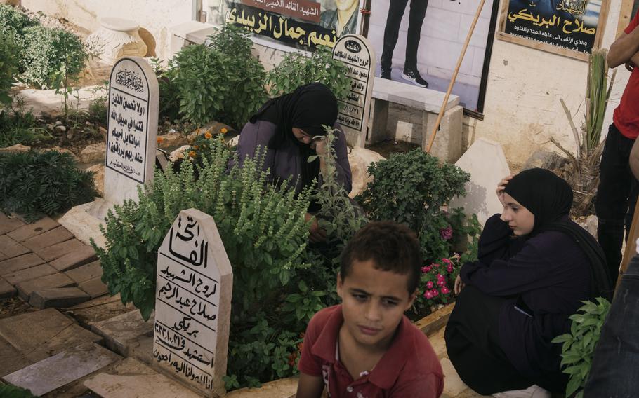 Relatives of a dead fighter sit near a grave in the cemetery of Jenin refugee camp.
