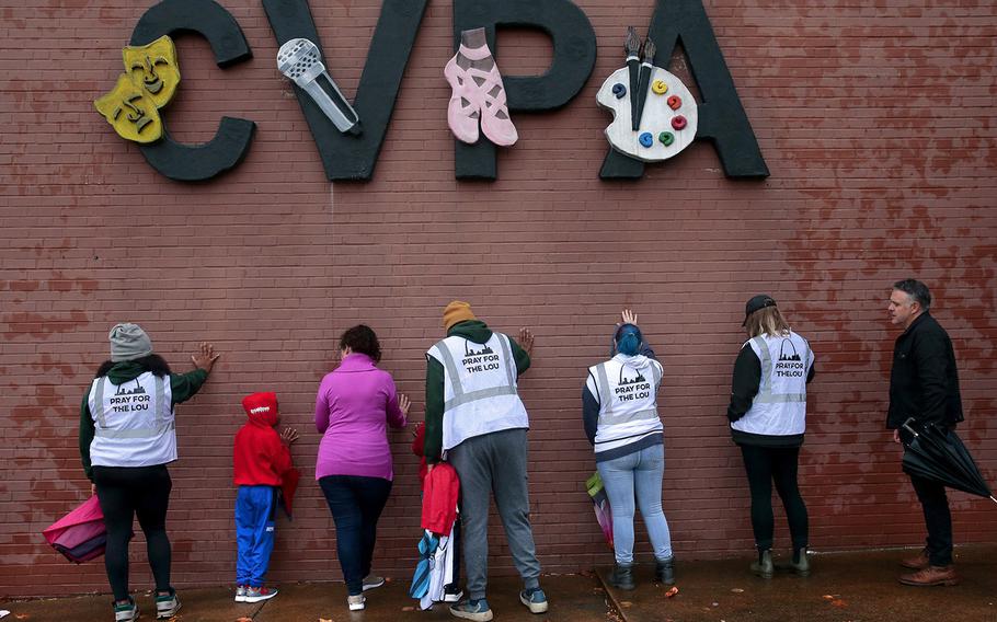A group of visitors from the group ‘Pray for the Lou’ place hands on the building during prayers at the site of Monday’s school shooting at Central Visual & Performing Arts High School, on Tuesday, Oct. 25, 2022, in St. Louis. 