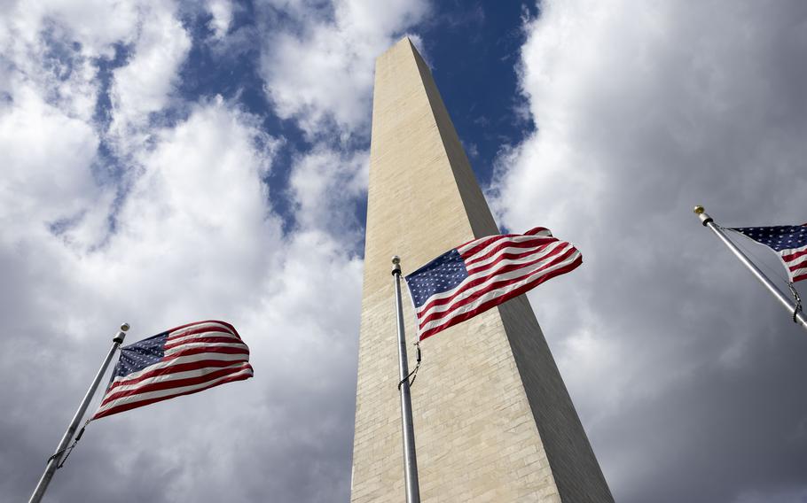 Winds whip American flags at the Washington Monument on Sunday.