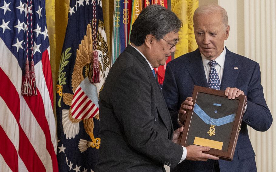 Joe Biden presents a framed Medal of Honor to an elderly man, awarded posthumously to his uncle.