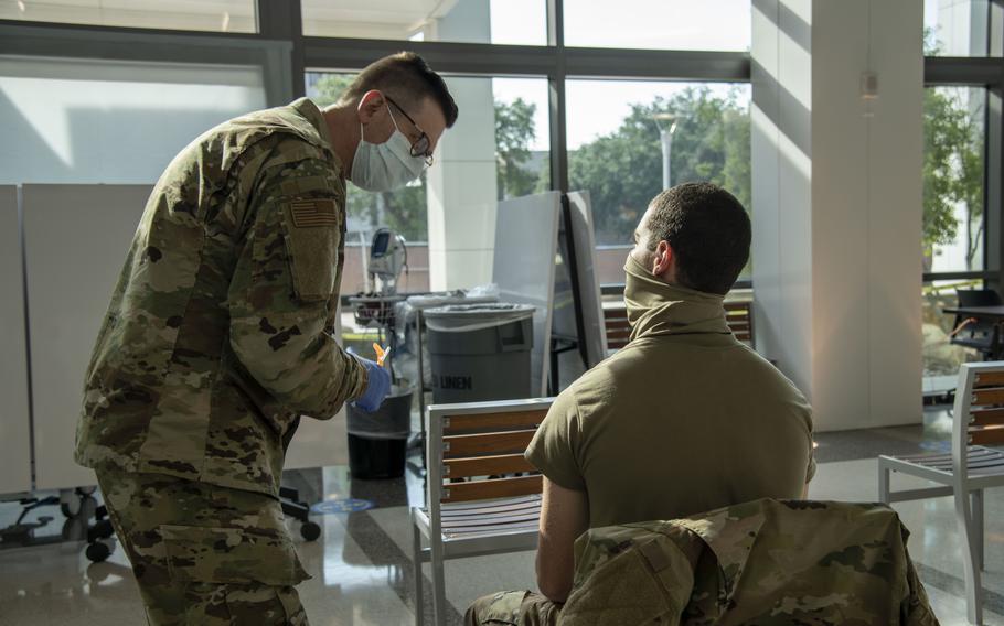 Lt. Col. Kevin White, a doctor who coordinates coronavirus vaccines for the 59th Medical Wing, discusses the vaccination process May 14, 2021, with a basic trainee from the 37th Training Wing at Wilford Hall Ambulatory Surgical Center at Lackland Air Force Base in San Antonio.