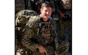 Sailor in combat uniform kneeling and holding a weapon.