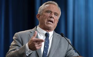 Robert F. Kennedy Jr. speaking in front of a microphone with one hand gesturing out.