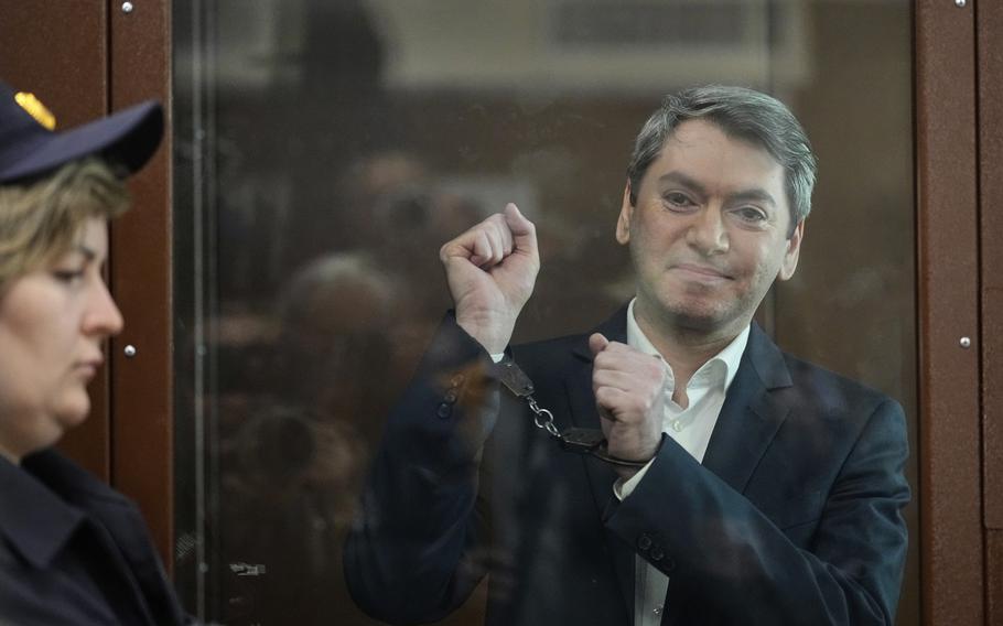 Grigory Melkonyants holds up his hands in handcuffs in a show of defiance.