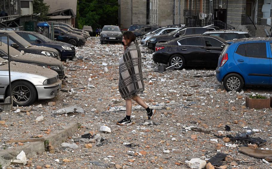 A resident walks among damaged cars while leaving a multi-story residential building, partially destroyed after night drone attacks, in Kyiv on Tuesday, May 30, 2023.