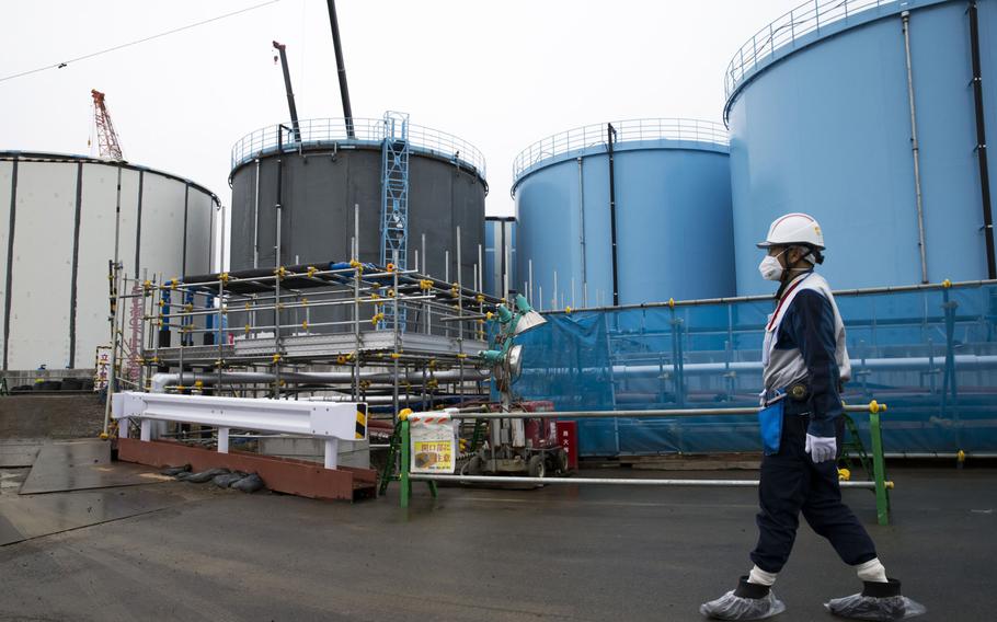 An employee walks past storage tanks for contaminated water at Tokyo Electric Power Co.'s Fukushima Dai-ichi nuclear power plant in Okuma, Japan, on Feb. 23, 2017. 