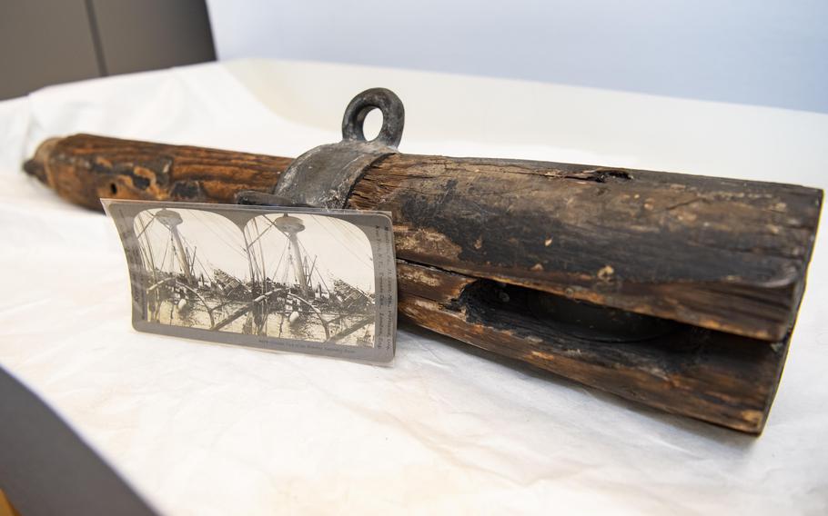 An artifact from the USS Maine, recently donated to the curatorial collection of Arlington National Cemetery, is paired with a historical stereographic image of the wrecked battleship. 