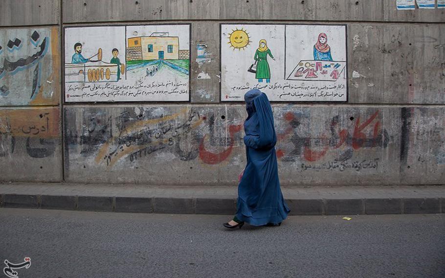 A woman clad in a burqa walks past a building in Kabul, Afghanistan in September 2021. The Taliban regime in Afghanistan, hoping not to further alienate foreign donors, has been sending out muddled signals rather than ironclad orders on controversial topics, especially women’s rights. The citizenry, hoping to get through another hard day without crossing an unpredictable red line, is mostly lying low.