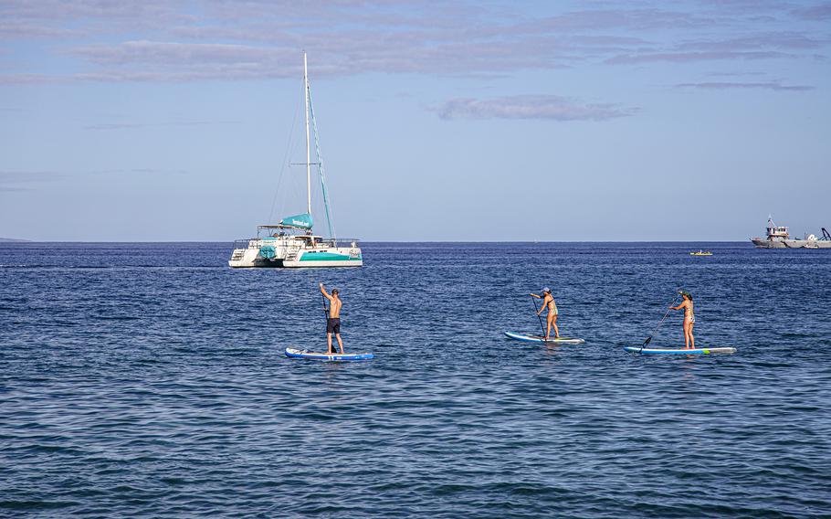 People paddleboard close to shore on Maui. 