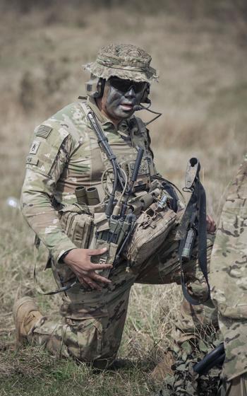 A US Army soldier kneeling in the field.