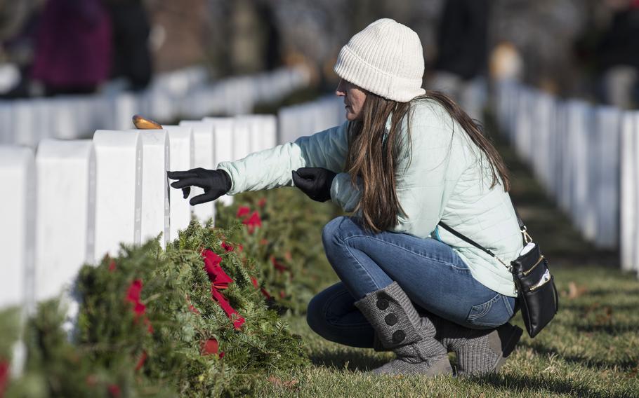Navy veteran Erin Strasburger touches the headstone of her late husband, Navy SEAL Chief Petty Officer Robert. W. Strasburger, at Arlington National Cemetery on Saturday, Dec. 17, 2022.
