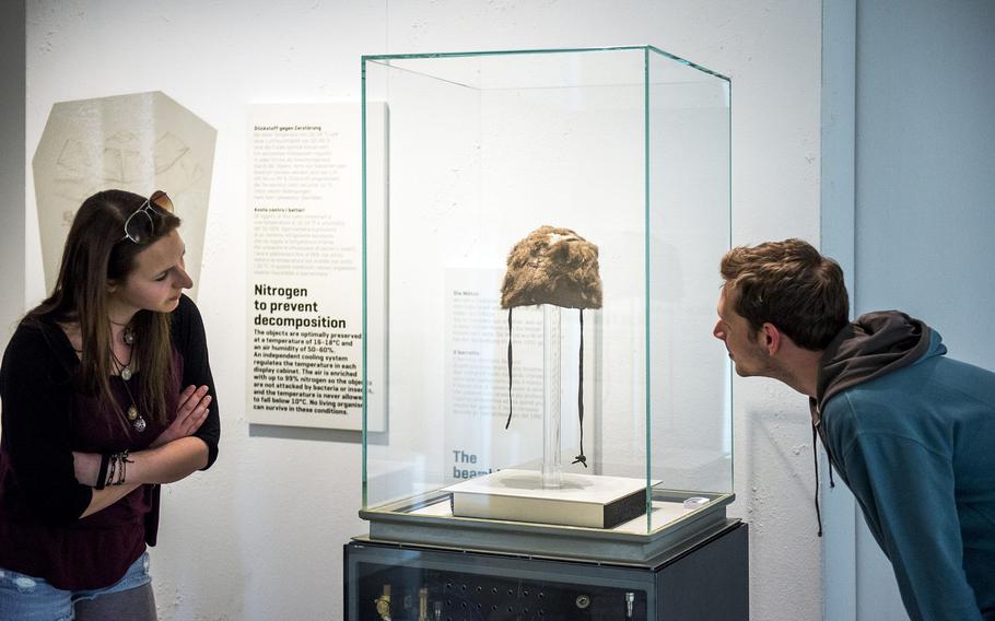 Visitors at the South Tyrol Museum of Archaeology in Bolzano, Italy, look at the remains of the hat that Ötzi the Iceman was wearing when he was killed about 5,300 years ago. Personal effects including his ax are on display at the museum as well.