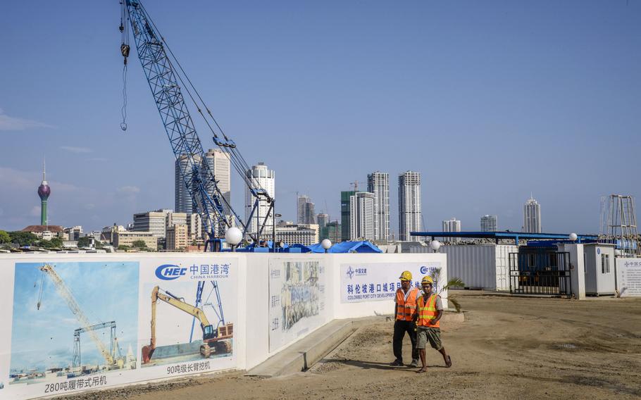Workers walk past signs for the Colombo Port City, developed by China Harbour Engineering, a unit of China Communications Construction, in Colombo, Sri Lanka, on March 30, 2018.