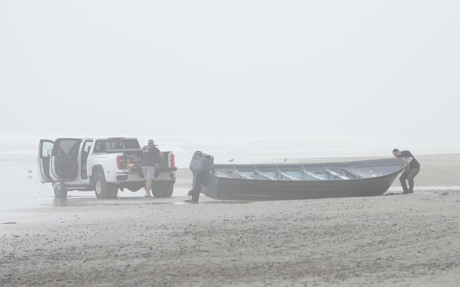 Boat salvager Robert Butler, left, and KC Ivers, right, prepare to move one of two boats on Blacks Beach, Sunday, March 12, 2023, in San Diego.