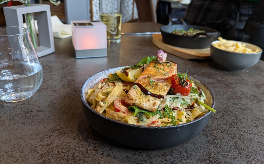 A bowl of lemon pasta with salmon sits on a table. 