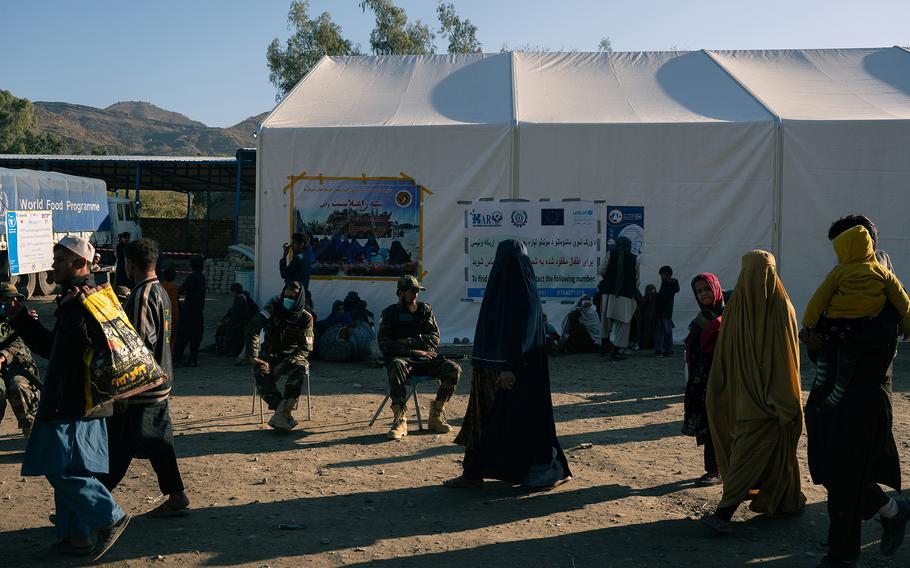 Afghan returnees pass Taliban soldiers at the Torkham crossing Nov. 11, 2023.