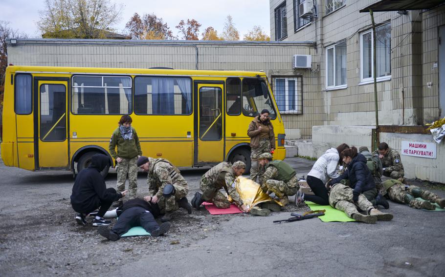 Украинские солдаты и мирные жители отрабатывают первую помощь под присмотром инструкторов на полигоне на окраине Киева, Украина, 27 октября 2022 года.