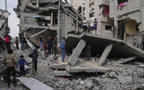 Gazans survey the damage of a destroyed building.