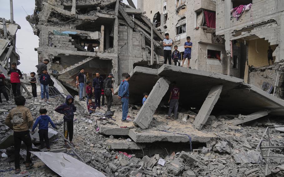 Gazans survey the damage of a destroyed building.