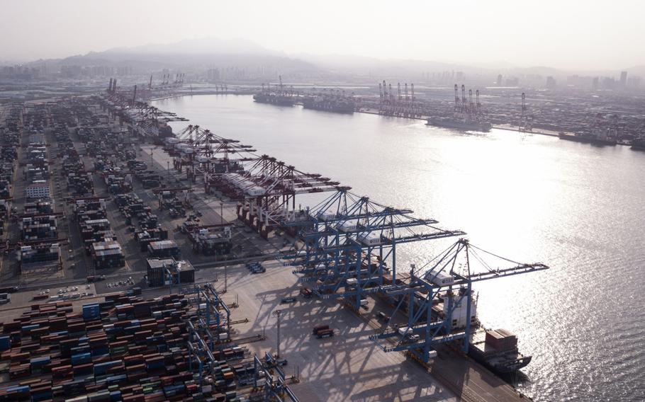 Cargo ships are moored under cranes as shipping containers stand at the Qingdao Qianwan Container Terminal in this aerial photograph taken in Qingdao, China, on Monday, May 7, 2018. 