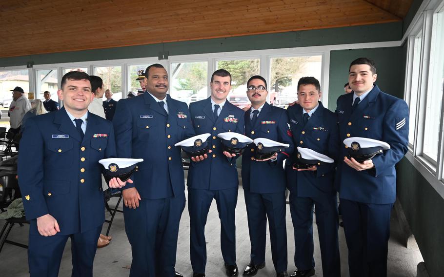 Crew members in uniform, with hats in hand, during the ceremony.