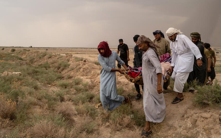 Relatives of Warda Obeid, a 60-year-old grandmother from Iraq's Anbar province, carry her body to a cemetery near al-Hol camp. Her nephew Saken Obeid, at right, in white, said she had died of a heart condition for which adequate treatment at the camp was unavailable. 