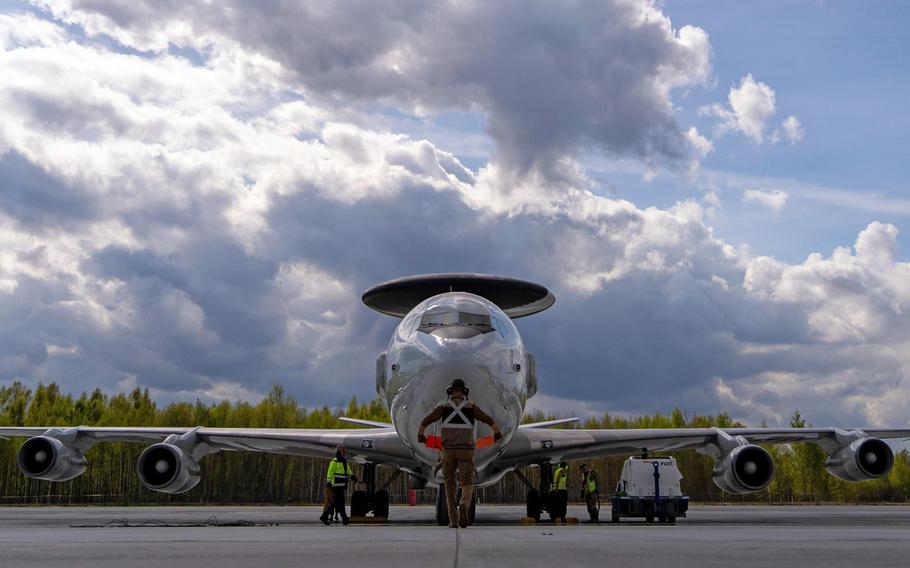 A flight crew guides an aircraft, seen from the front, on a runway.