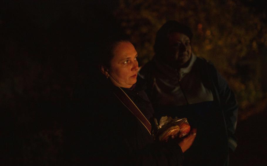 Tatyana Kovalenka, left, holds homemade pastries she received from a relative. She is joined by Olya Prytula as they walk in the dark back to their homes in Dnipro on Saturday.