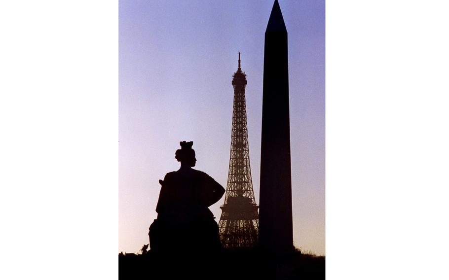  A statue at the Tuileries, the Eifel tower and the obelisk on the Place de la Concorde are silhouetted in a Paris purple sky.