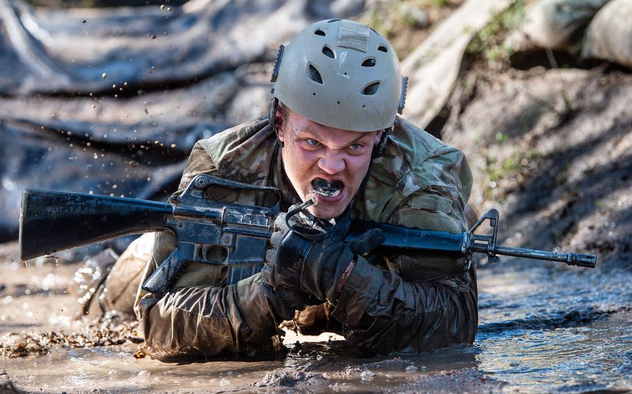 A cadet crawls through mud