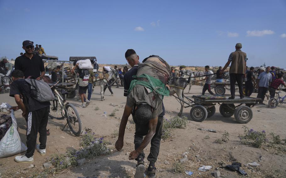 A man carries a body across sandy terrain.