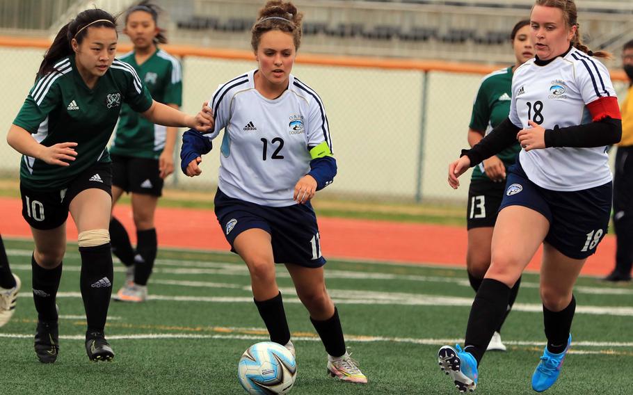 Osan’s Riley Hunt dribbles between Daegu’s Summer Brennan and Cougars teammate Aysha Craft during Thursday’s DODEA-Korea soccer match. The teams played to a 2-2 draw.