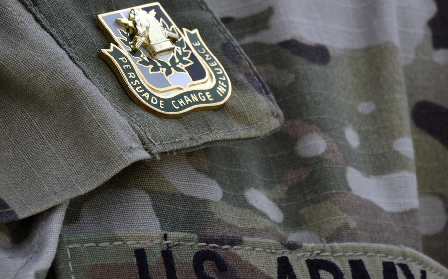 Army psyop graduates receive pins at the end of a field exercise reading "Persuade, Change, Influence." 