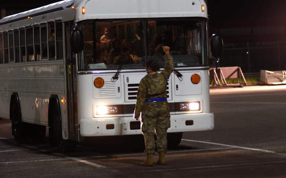 An airman directs a bus carrying evacuees from Afghanistan at Ramstein Air Base, Germany, on Friday, Aug. 20, 2021. Hundreds of evacuees began arriving Friday from Al Udeid Air Base, Qatar, after fleeing the Taliban.