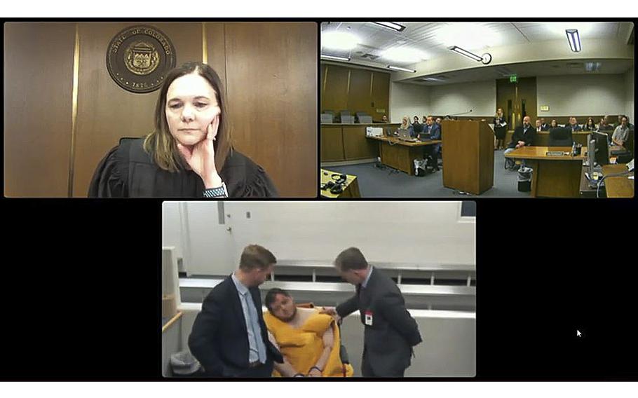 Anderson Lee Aldrich, the suspect in the Colorado Springs nightclub attack that left five dead, is seen in an orange jumpsuit with his two lawyers beside him in a video teleconference lower screen, while El Paso County Court Judge Charlotte Ankeny, in upper left screen, asks him questions.